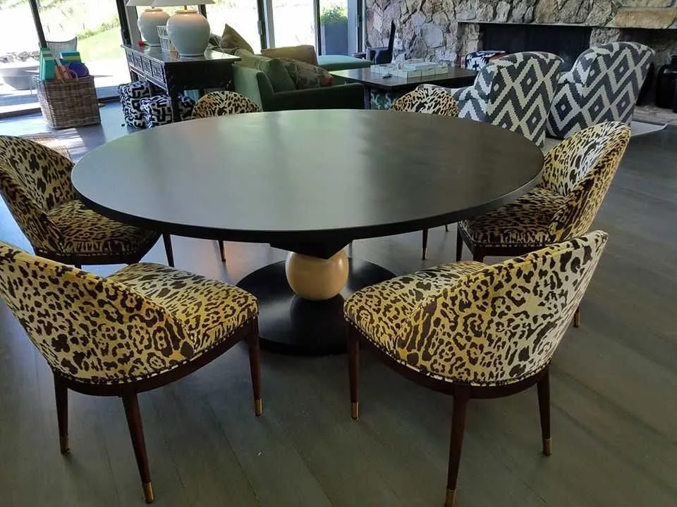 Round dining table with leopard print chairs in a modern living room.